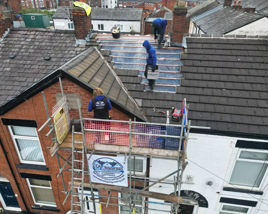 The ASAP Roofing team re-roofing a terraced house from scaffolding, with the company banner on the scaffold