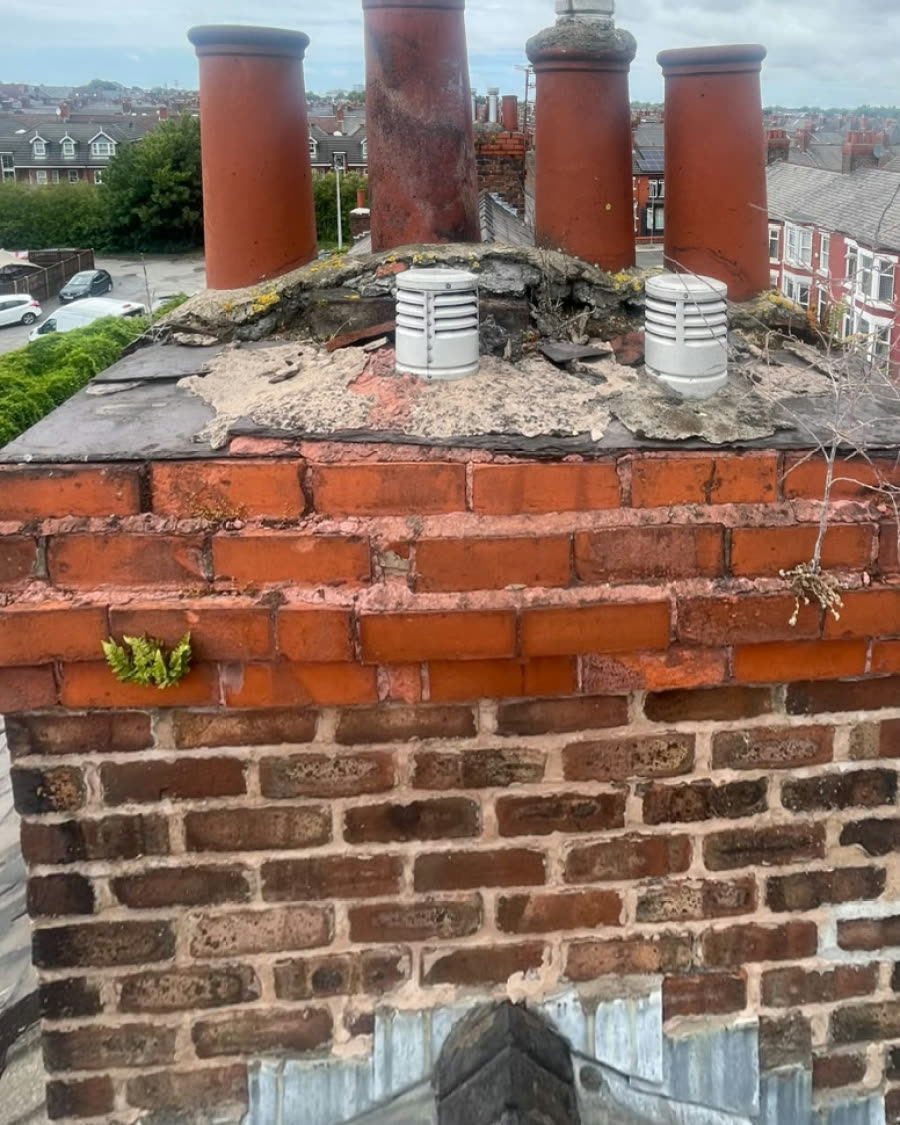 Chimney top with broken, crumbling flaunching and weeds growing around the pots