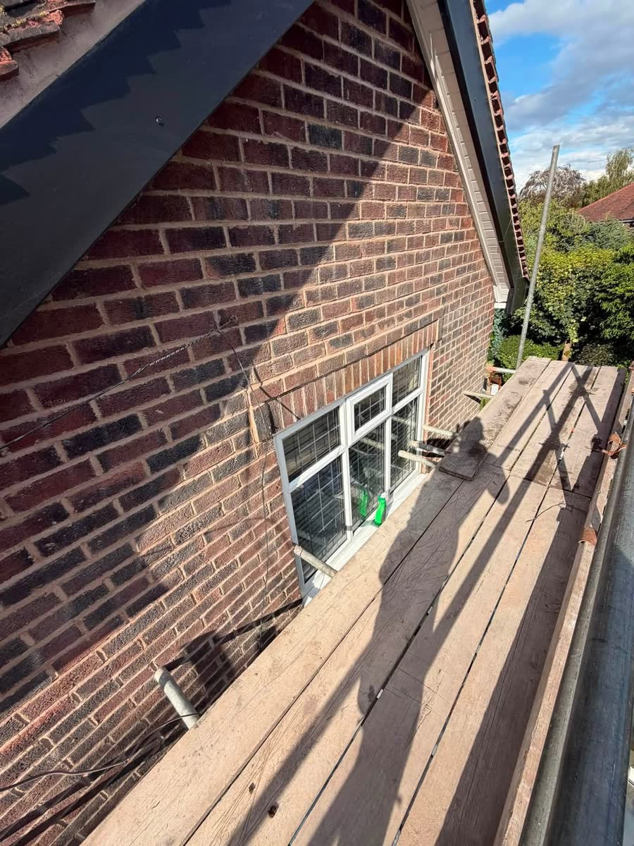 New black fascia along a brick house, seen from the scaffold