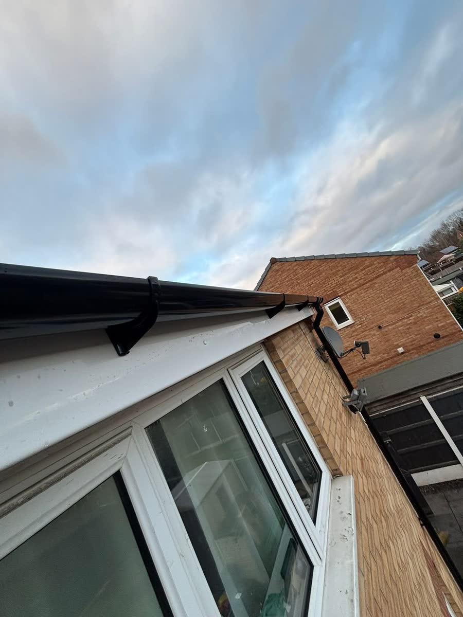 New white soffit and black guttering over a window, looking up from below