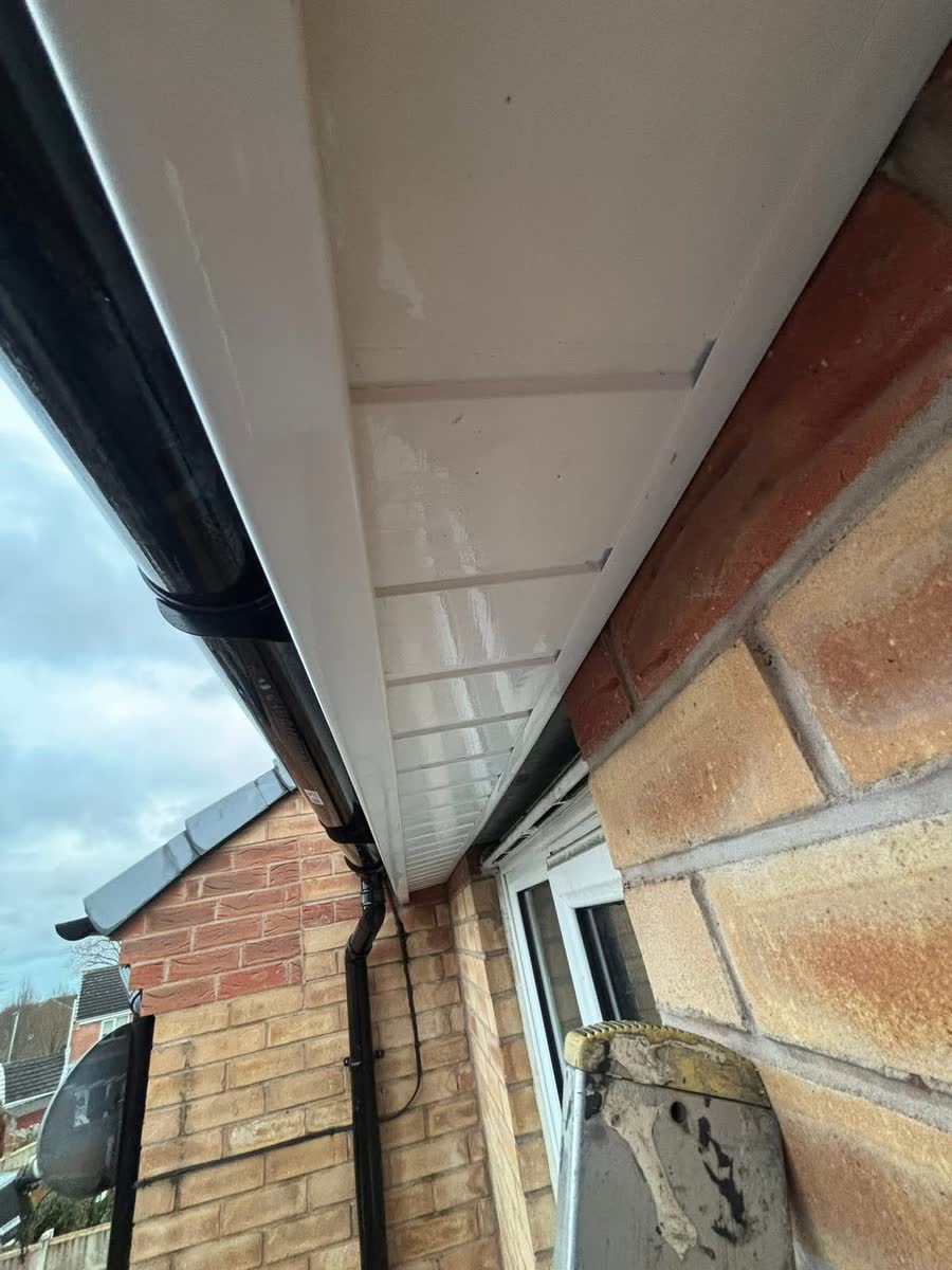 New white soffit boards with black fascia and downpipe along a brick wall