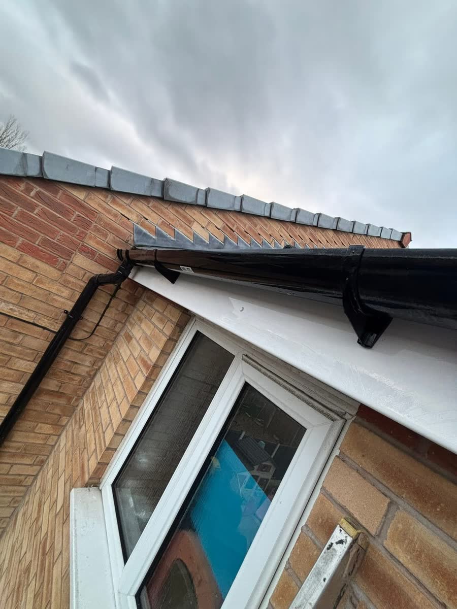 New black gutter and fascia with white soffit above a window