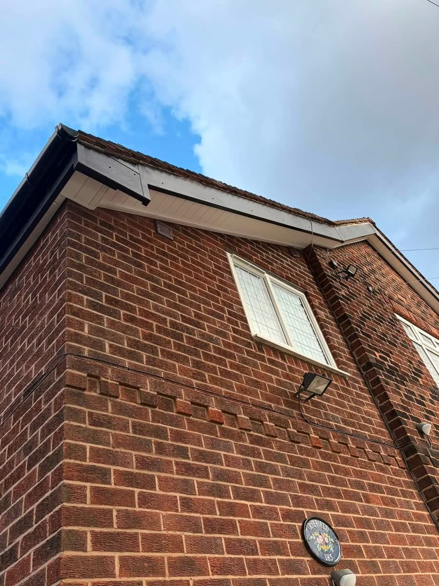 A brick gable end with new black fascia and white soffit