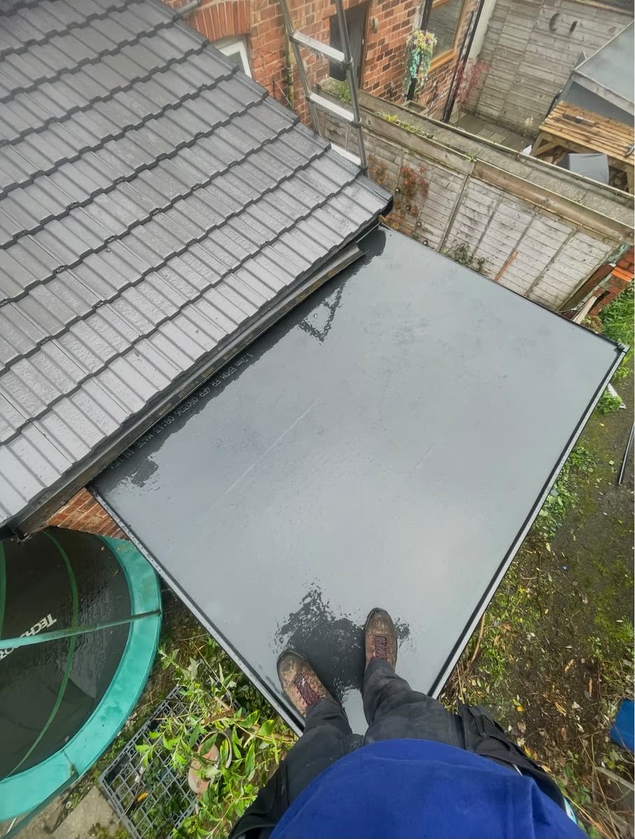 A new grey flat roof beside a tiled lean-to, seen from the roof edge