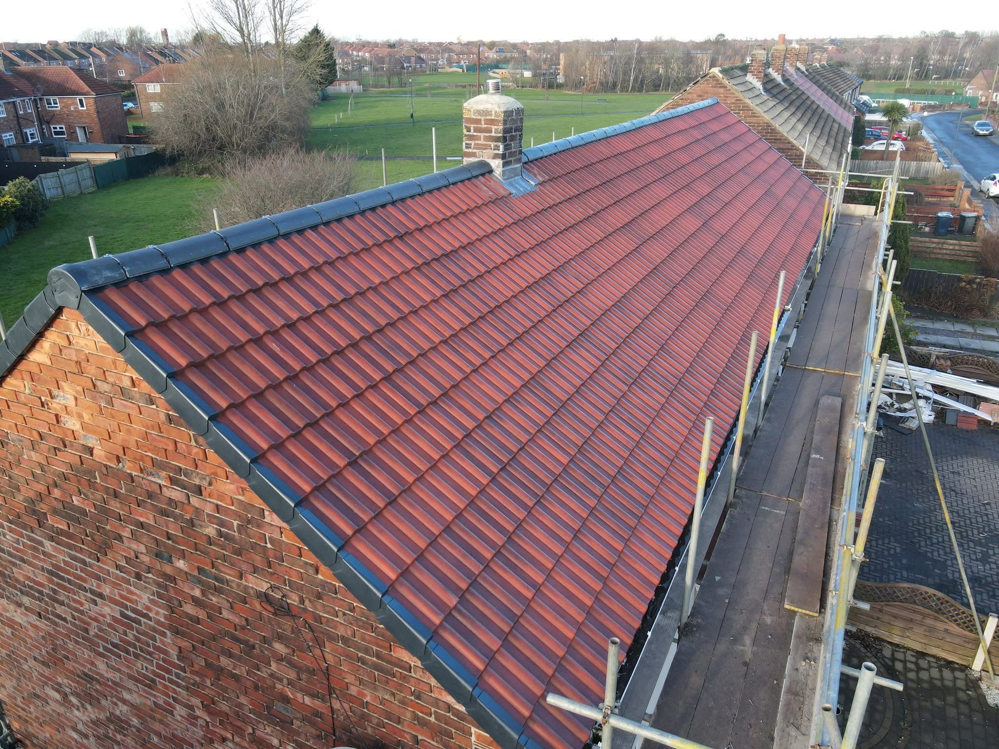 Newly tiled red roof with scaffolding along the eaves