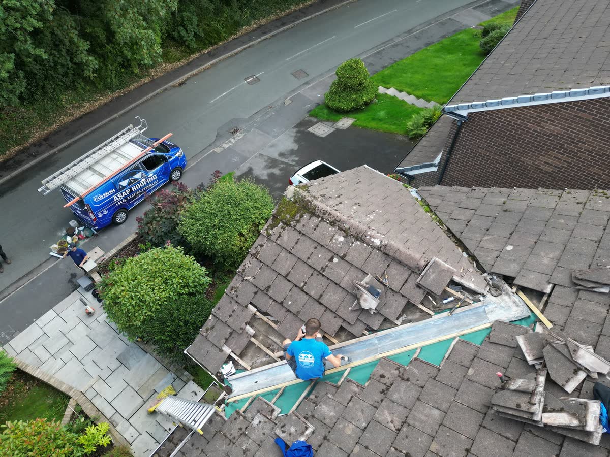 One of the team working in a roof valley, seen from the air, with the van on the road
